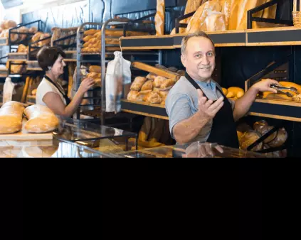 un boulanger cheveux gris devant ses pains en boutique