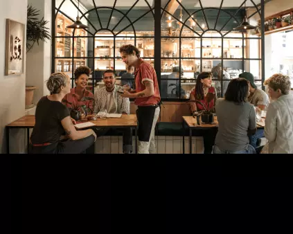 une salle de restaurant avec une table de plusieurs personnes et un jeune serveur