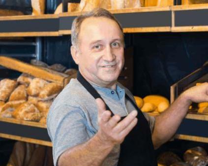 un boulanger cheveux gris devant ses pains en boutique