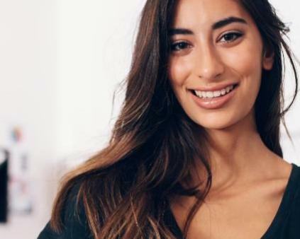 une jeune femme brune qui croise les bras devant des bacs dans un salon de coiffure