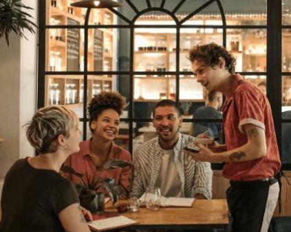 une salle de restaurant avec une table de plusieurs personnes et un jeune serveur