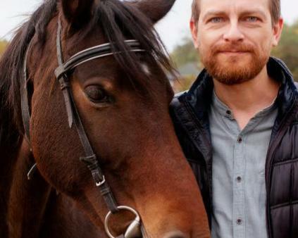 un homme barbu avec un cheval dans un champ