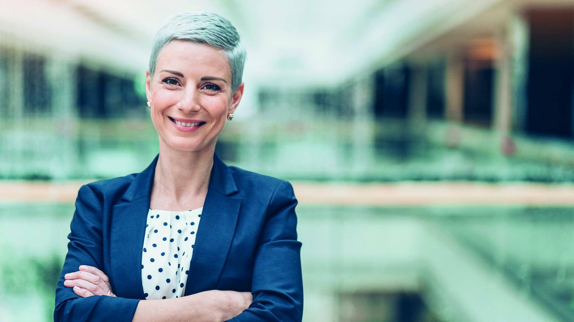 une femme cheveux gris croisant les bras dans une entreprise