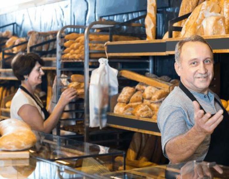 un boulanger cheveux gris devant ses pains en boutique