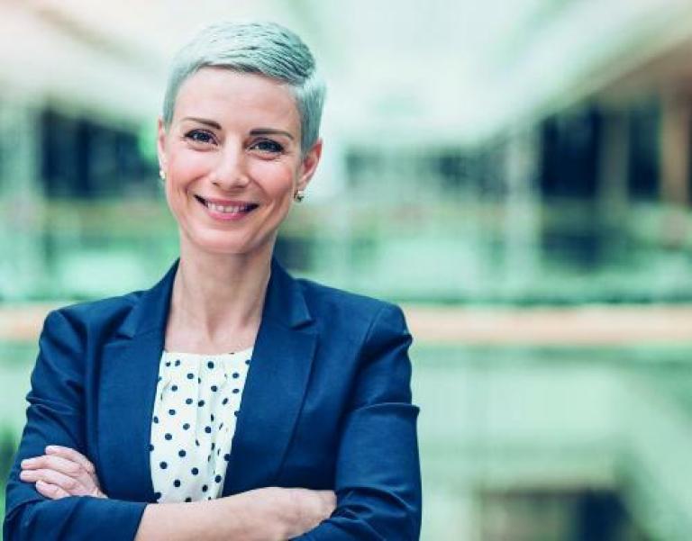 une femme cheveux gris croisant les bras dans une entreprise