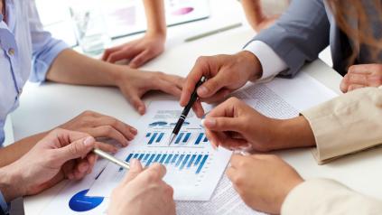 plusieurs mains de personnes autour d'une table qui montrent un document avec des graphiques