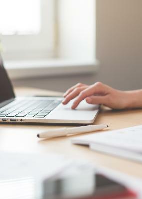une main de femme qui touche un clavier d'ordinateur portable sur un bureau